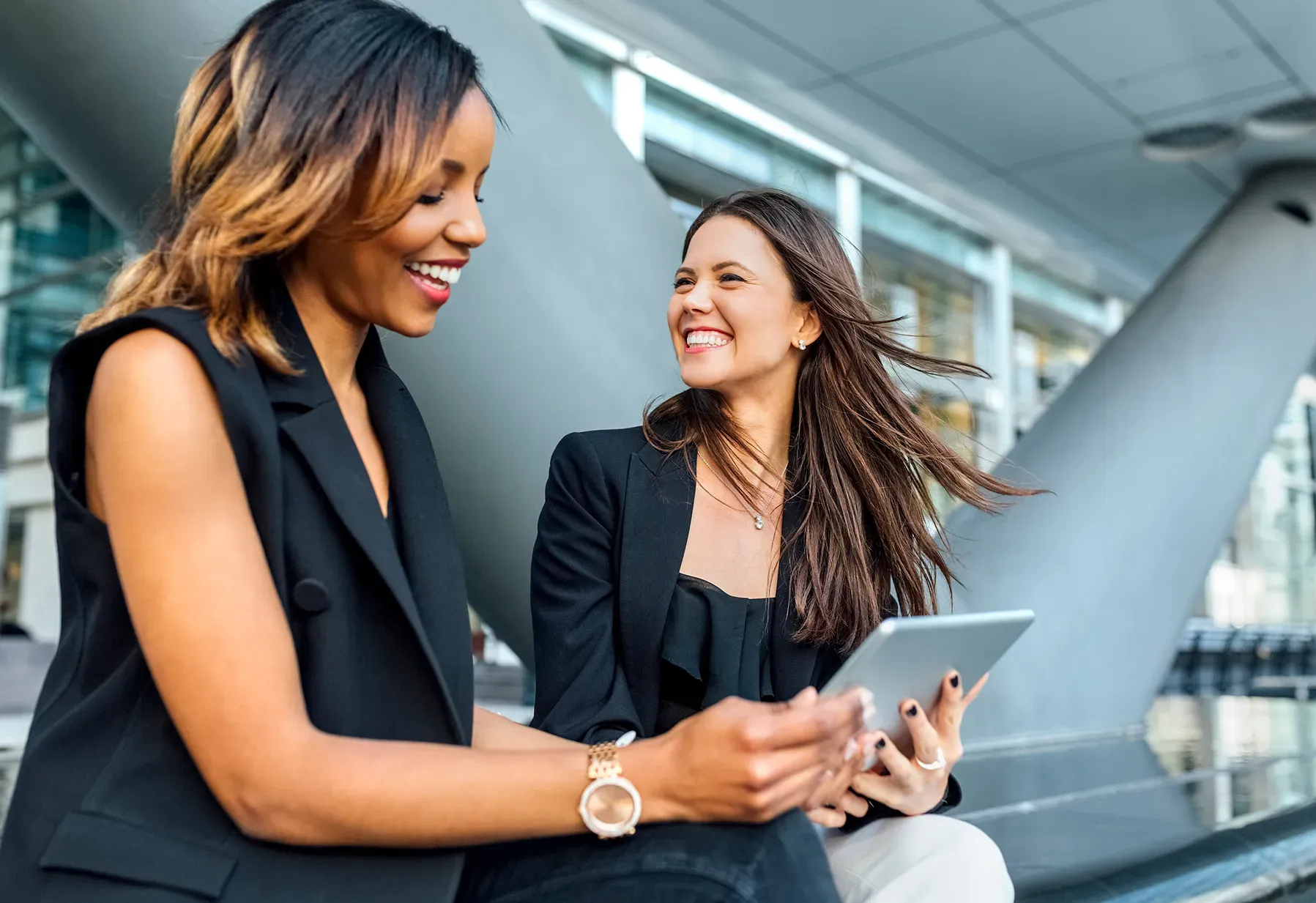 Two women sitting together and looking at a tablet.